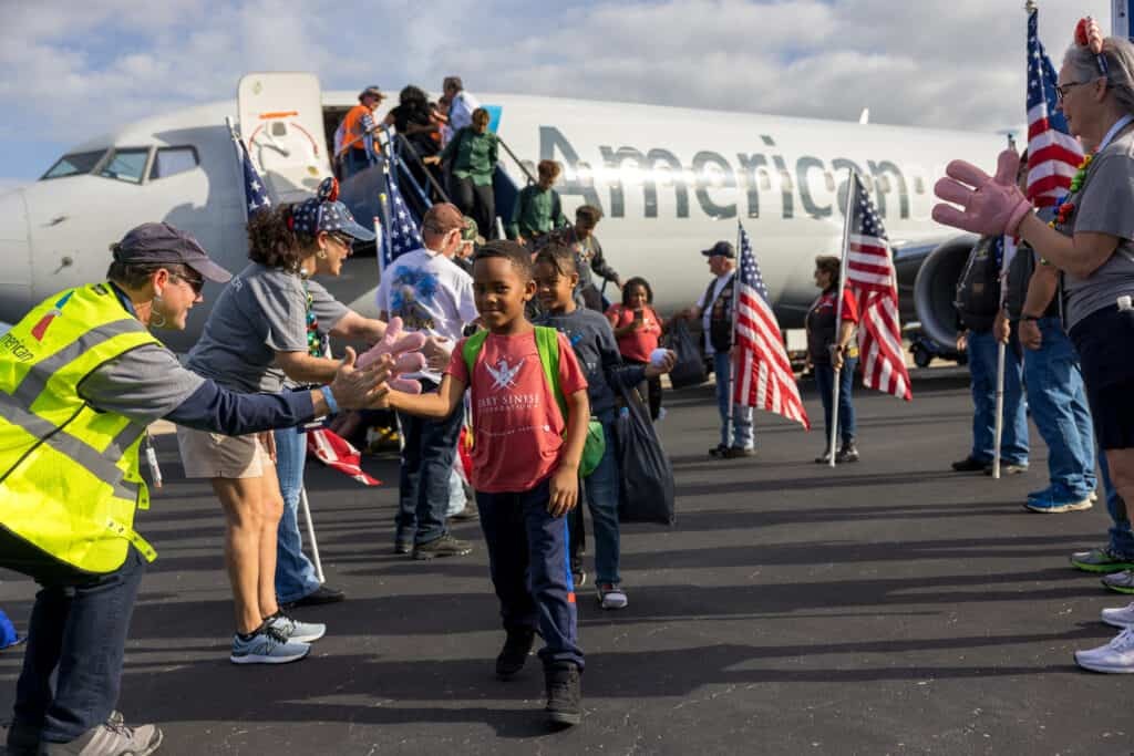 Veterans receiving a warm welcome with American flags, symbolizing the support provided by organizations like Vehicles for Veterans