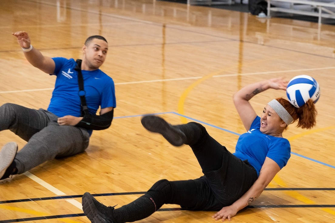 A female service member participates in a volleyball game during the Warrior Care program training, highlighting adaptive sports as part of veteran rehabilitation.