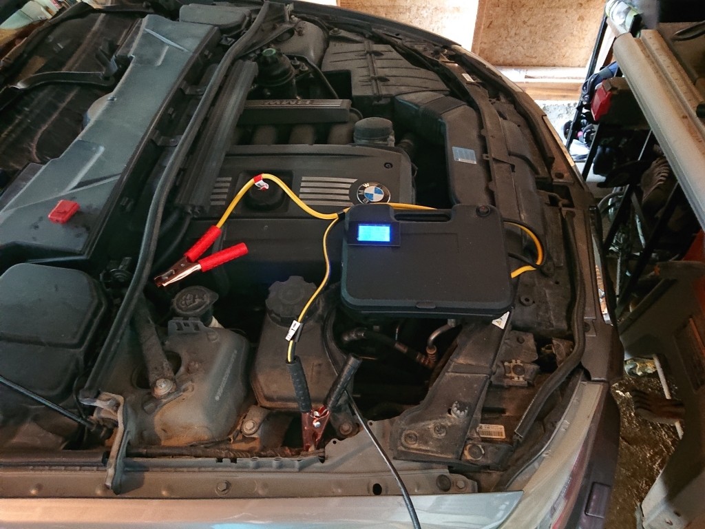 Assembled DIY car programming power supply connected to a car, displaying voltage and amperage readings on the digital multimeter.