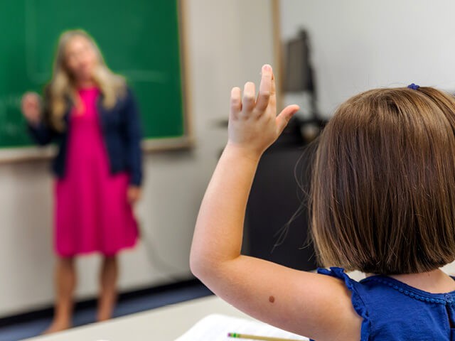 Smiling teacher interacting with students in a classroom setting, highlighting the positive impact of career switchers in education