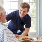 Woman caregiver helping senior woman with exercises