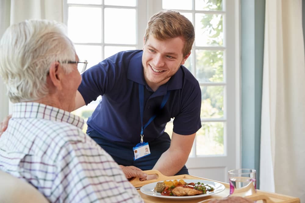 Woman caregiver helping senior woman with exercises