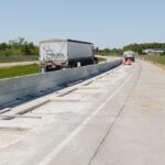 Construction work on a highway with traffic in the background.