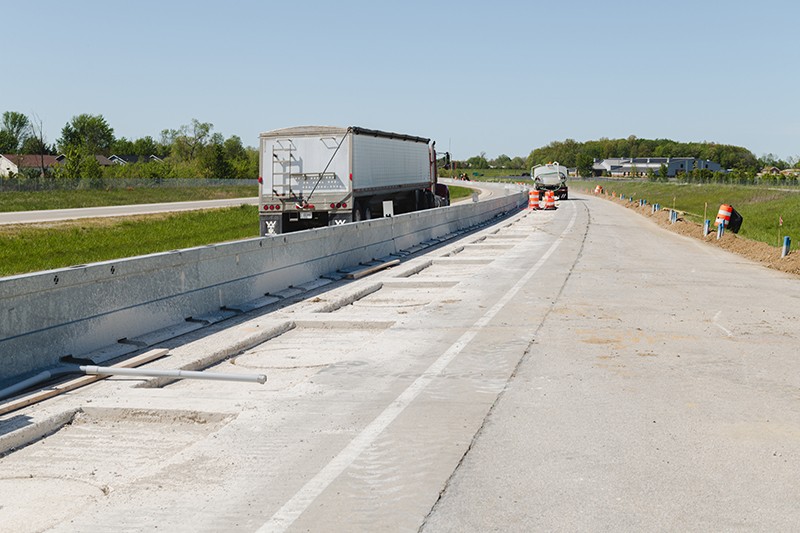 Construction work on a highway with traffic in the background.