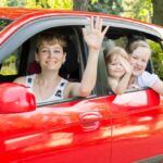 Single mom smiles with her children next to their donated car.