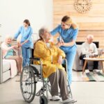 Nurse assisting elderly woman in wheelchair, providing water at a retirement home, highlighting senior care and support