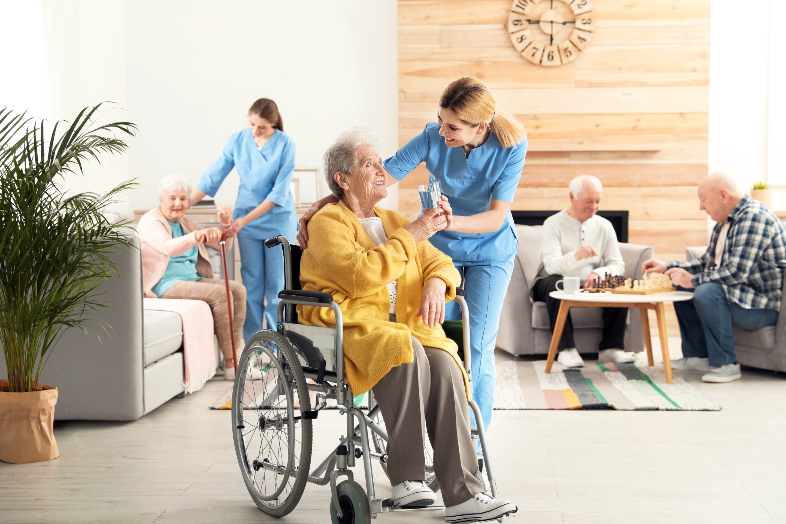 Nurse assisting elderly woman in wheelchair, providing water at a retirement home, highlighting senior care and support